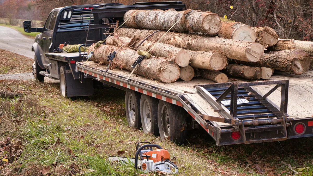 Flatbed dually towing a gooseneck flatbed trailer loaded with logs — Illinois Hot Shot Trucking Insurance from Truck Guard Insurance
